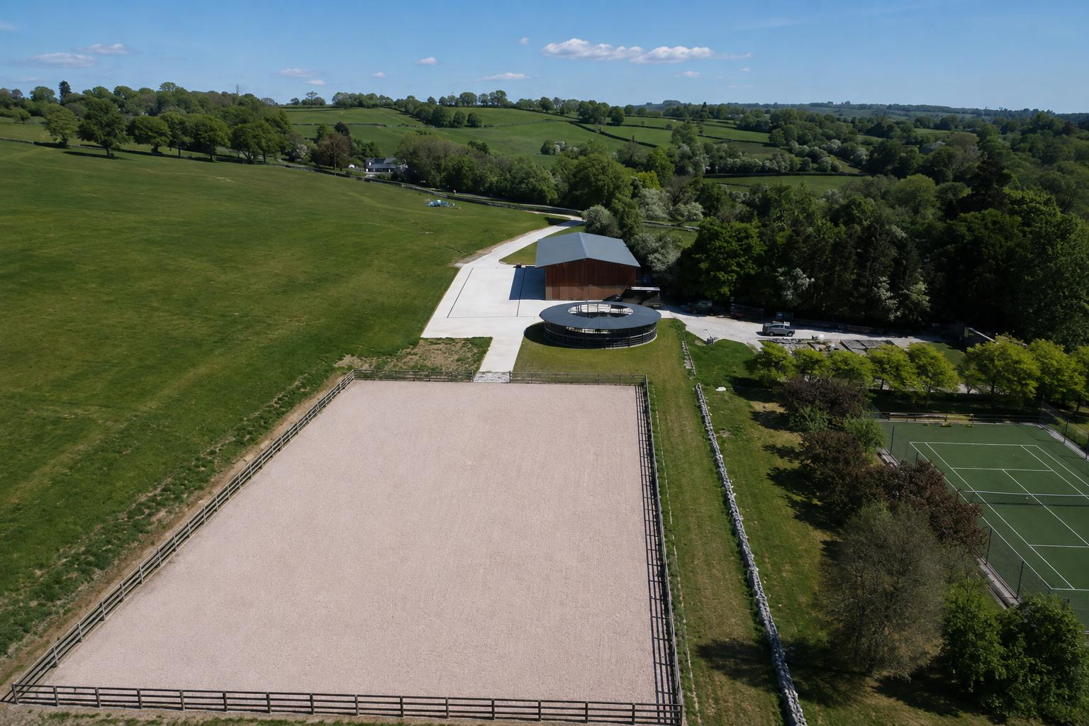 Aerial view of an equestrian facility with ménage, horse walker and barn
